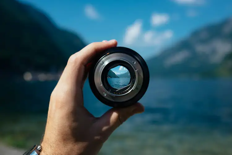 Camera Lens being held up you can see the sea